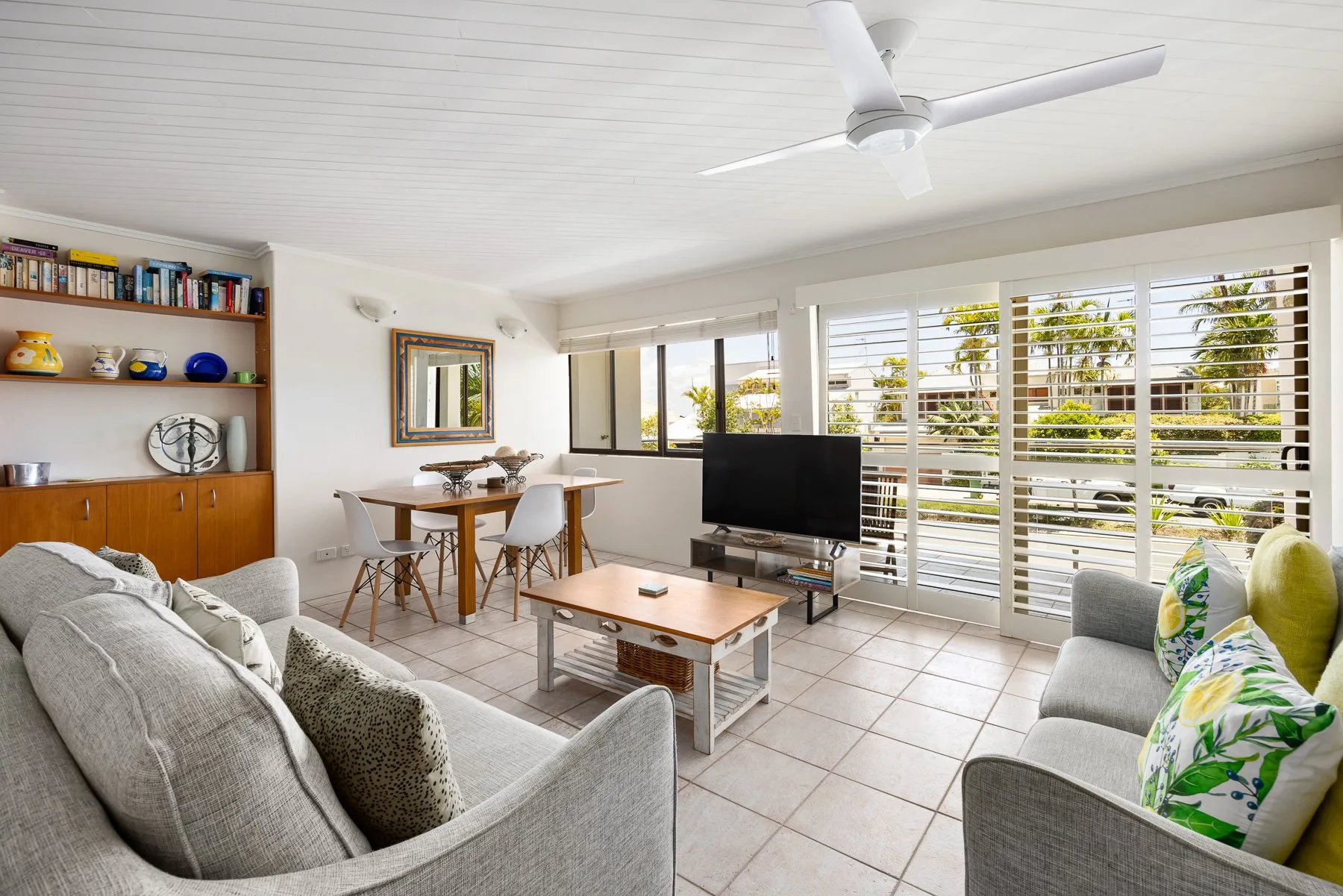 A bright living and dining area with seating, a table, and wide windows.