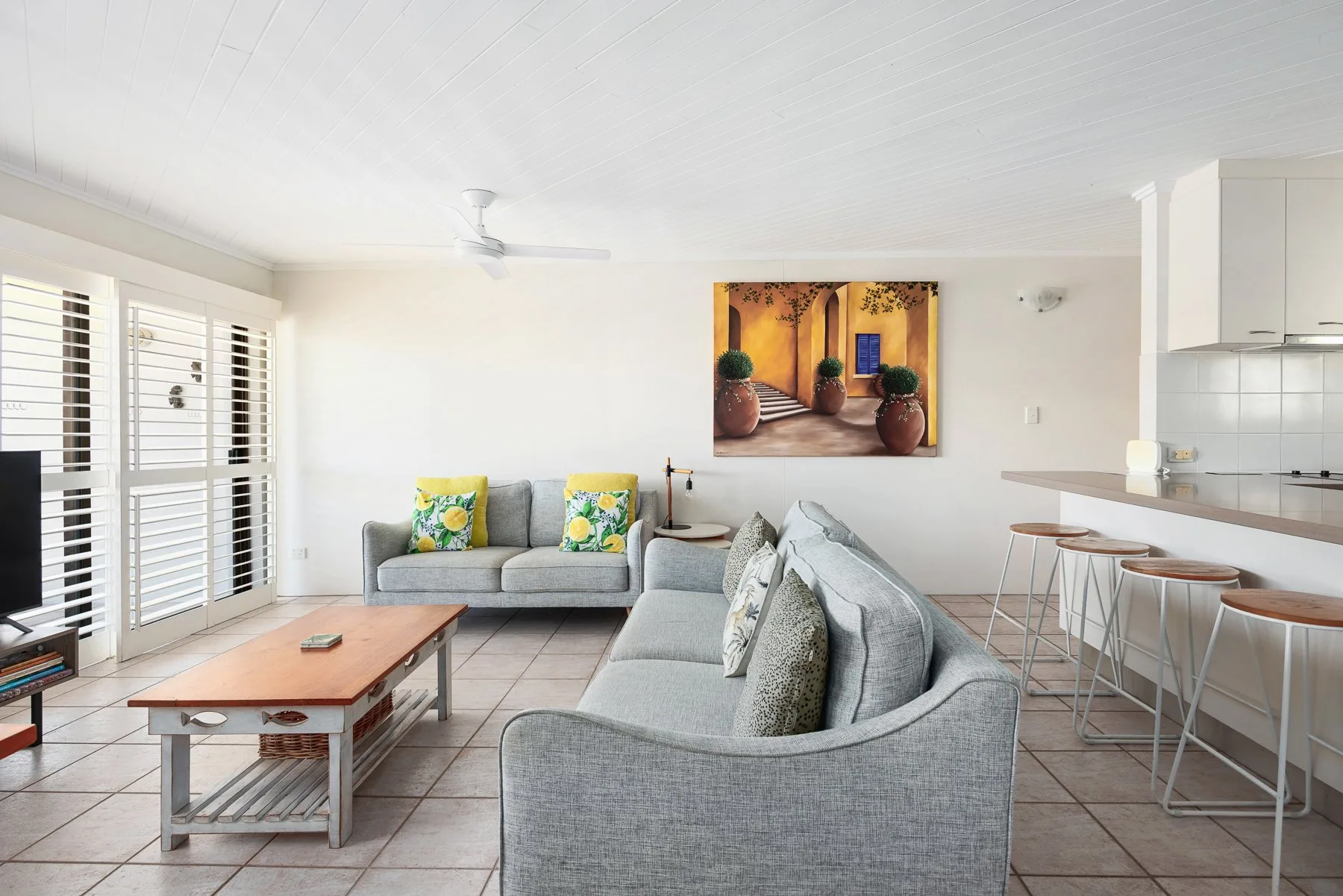 A bright living area with gray seating and a dining counter.