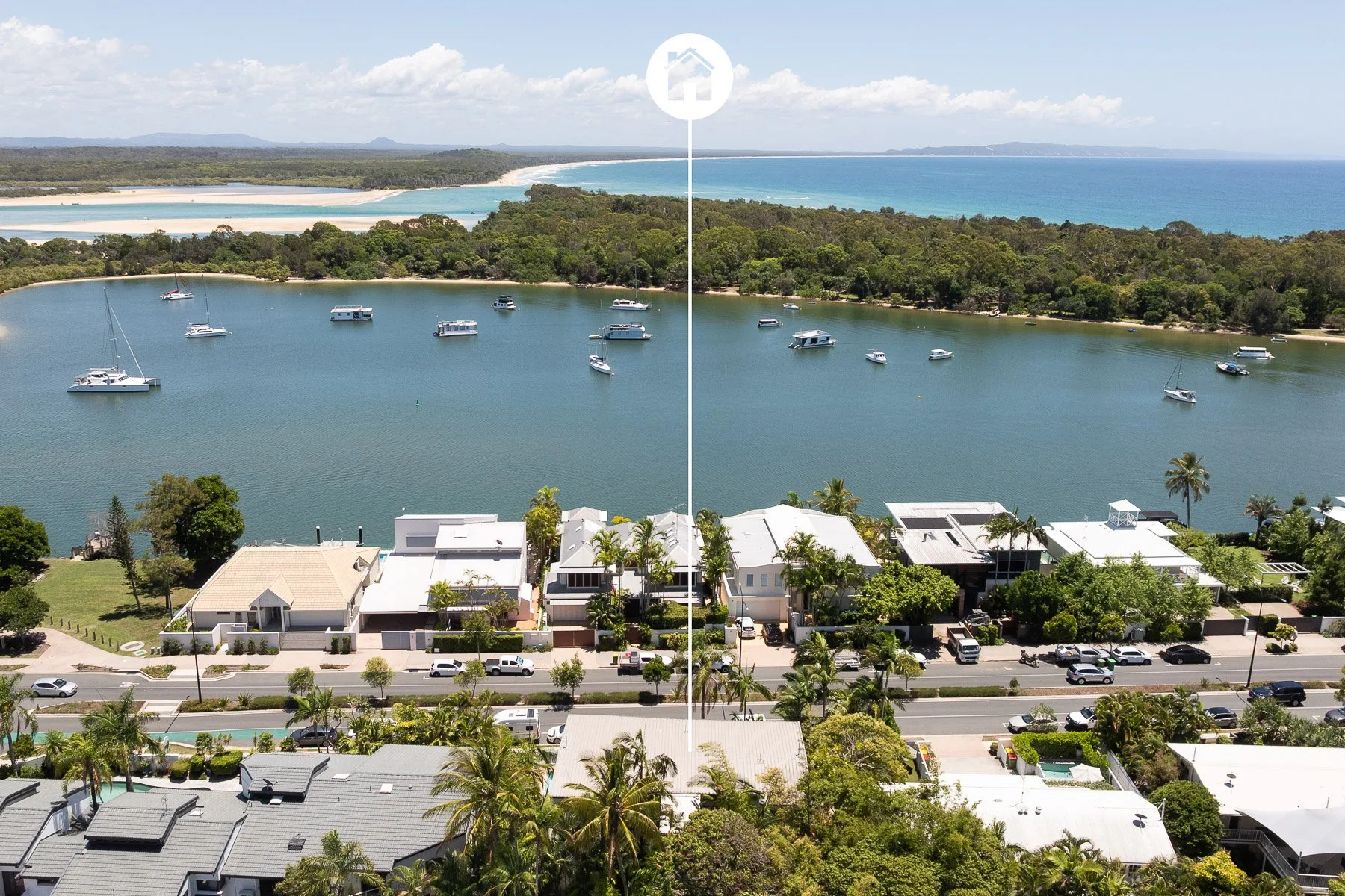 Aerial view of a waterfront neighborhood, with boats in the bay and ocean beyond.
