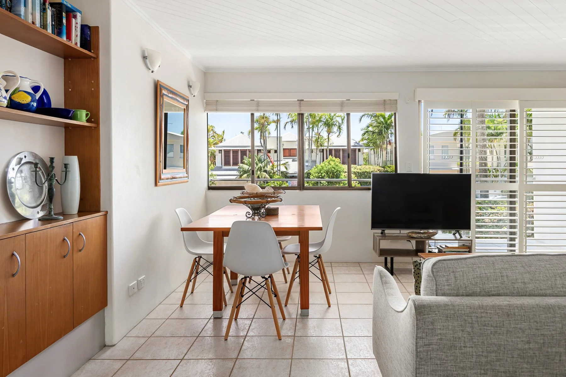 A bright living and dining area with a television and large windows.