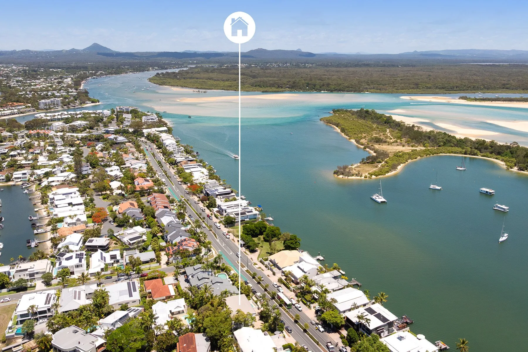 An aerial view shows a coastal town beside turquoise waterways and a sandy shore.