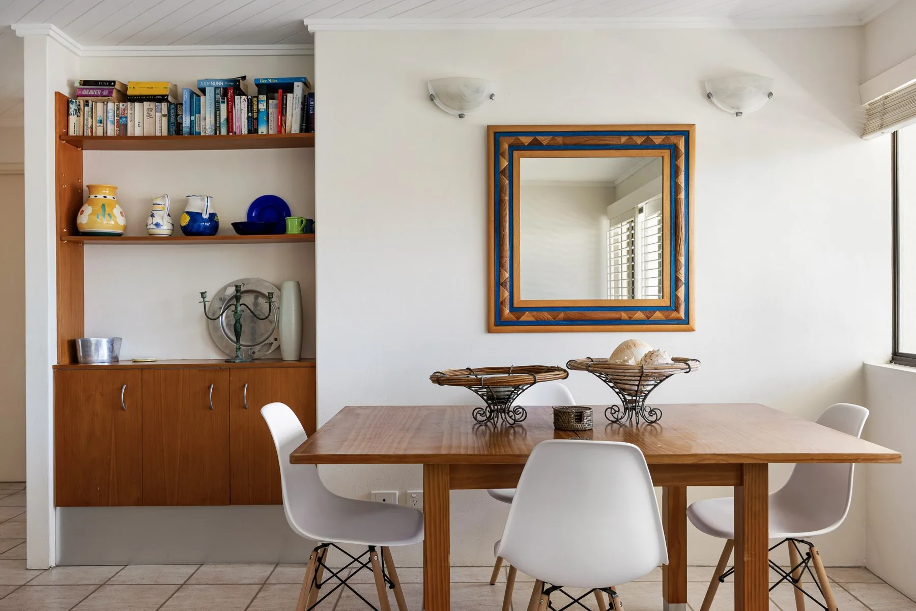 A dining area with a wooden table, chairs, and a wall mirror.