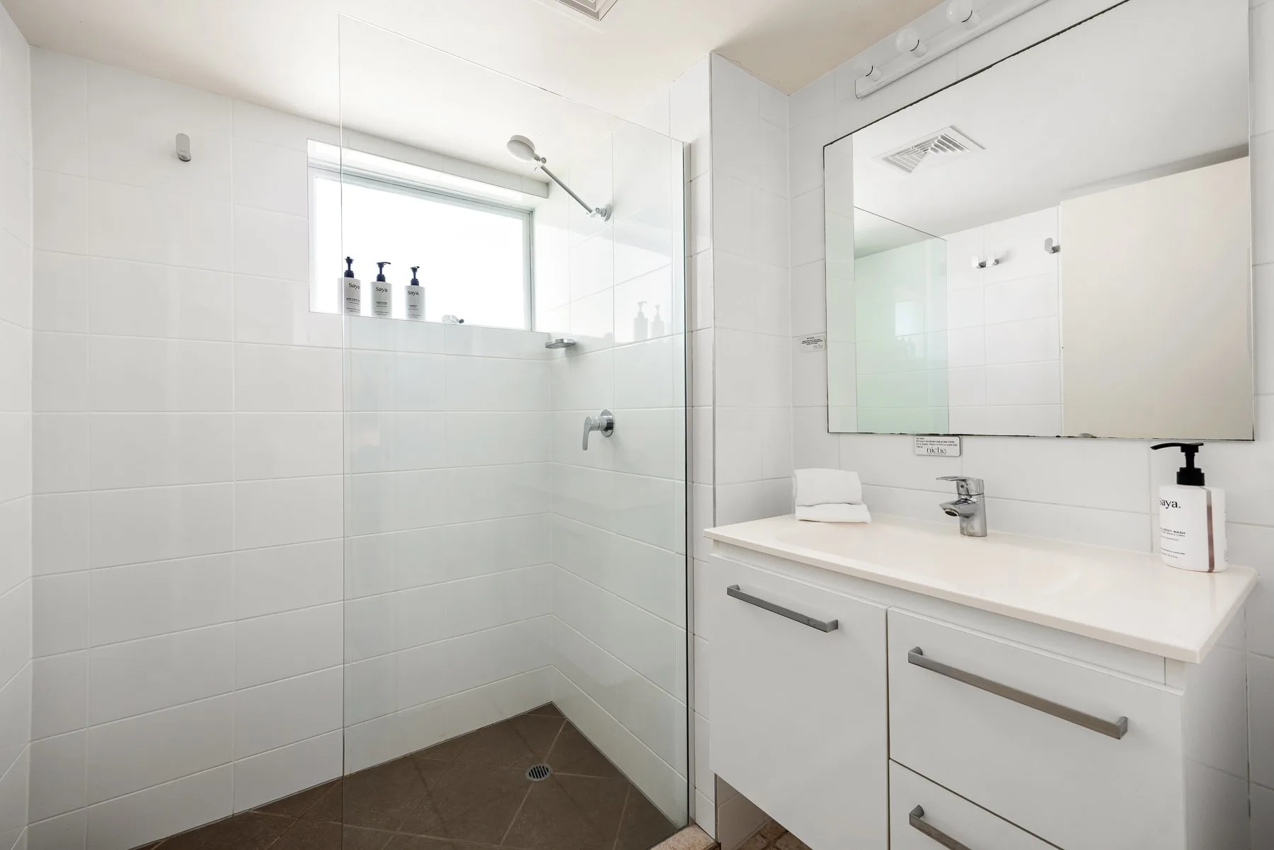 A bright bathroom with a glass shower area and a white vanity.