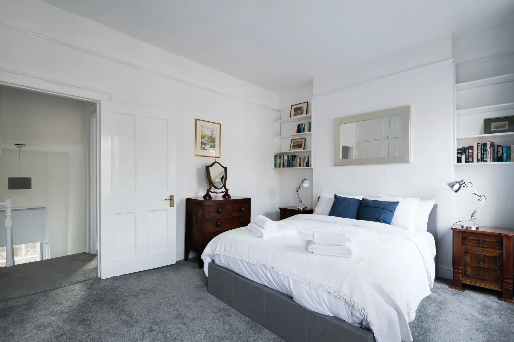 A bright bedroom with a neatly made bed and bedside tables.