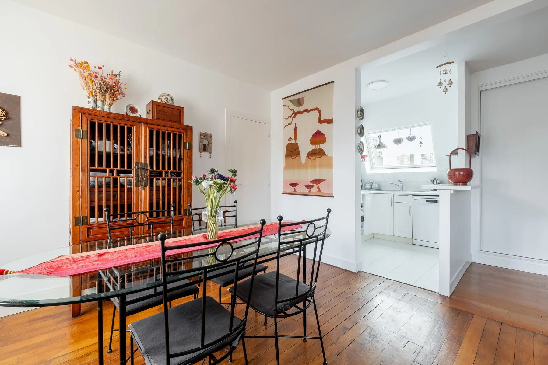 A dining area with a wooden table and black metal seating beside an open kitchen.