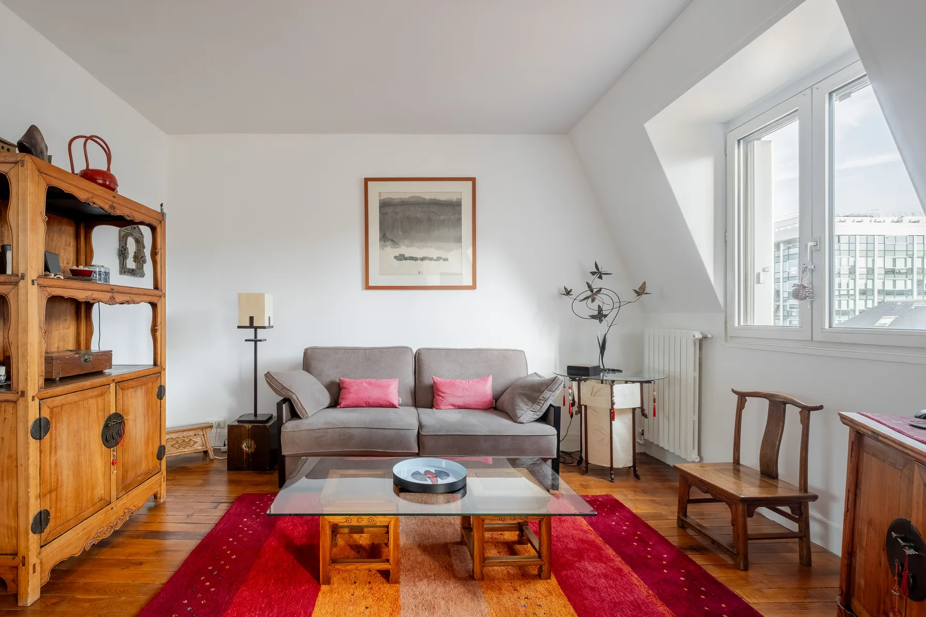 Una sala luminosa con asientos, una mesa de centro y una ventana grande.