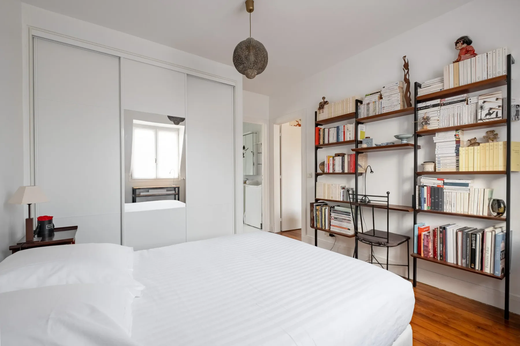 Un dormitorio luminoso con una cama y estanterías abiertas junto a la pared.