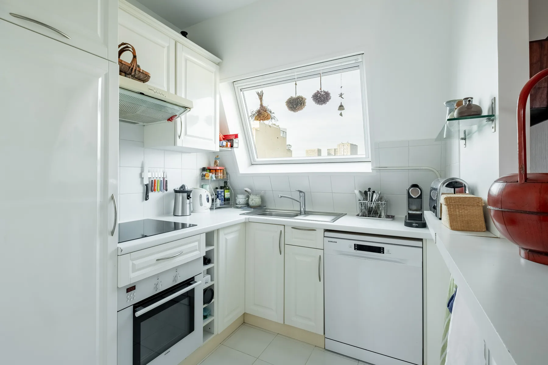 Una cocina luminosa con gabinetes blancos, encimeras y una ventana amplia.