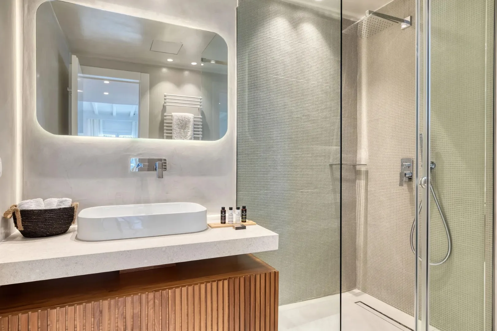 Un baño con lavabo y ducha con mampara de vidrio.