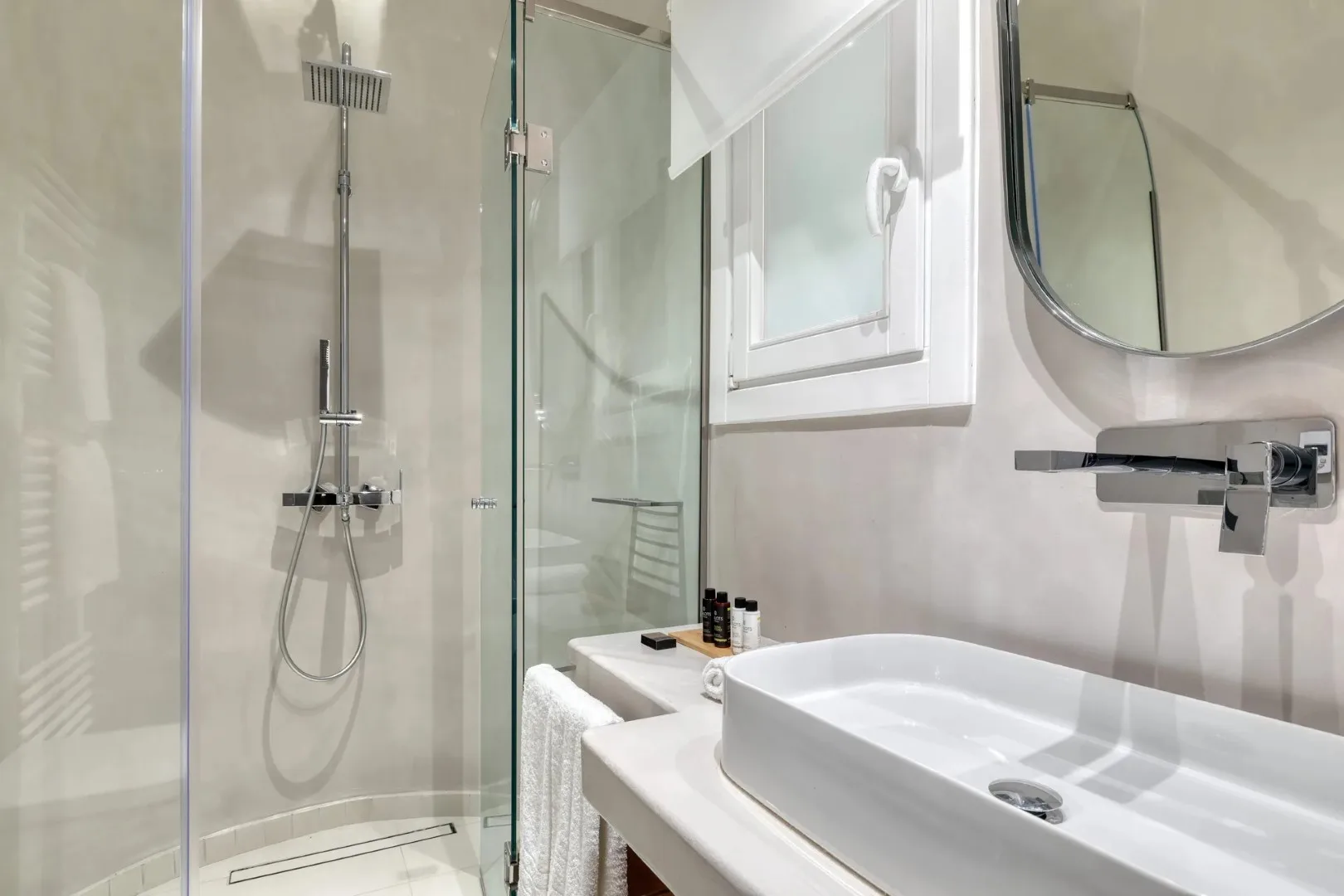 Un baño luminoso con una ducha de vidrio y un lavabo blanco.