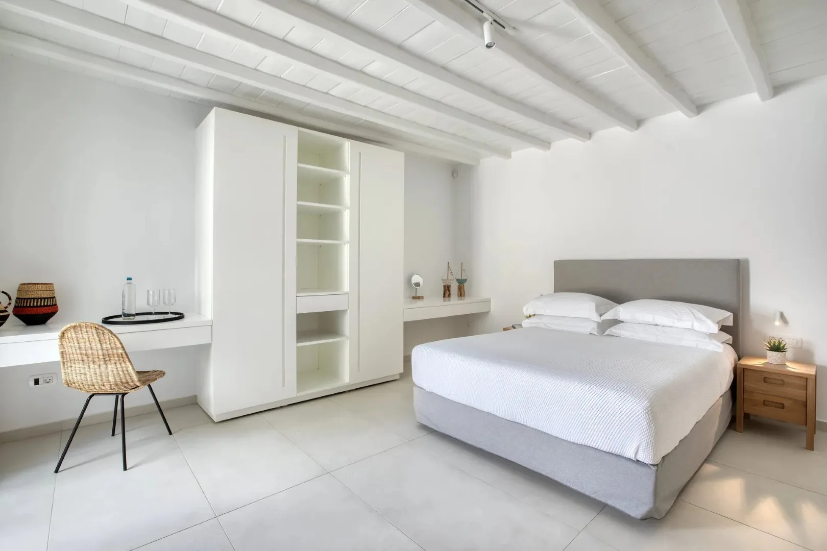 Un dormitorio luminoso con una cama doble, estanterías empotradas y un escritorio.