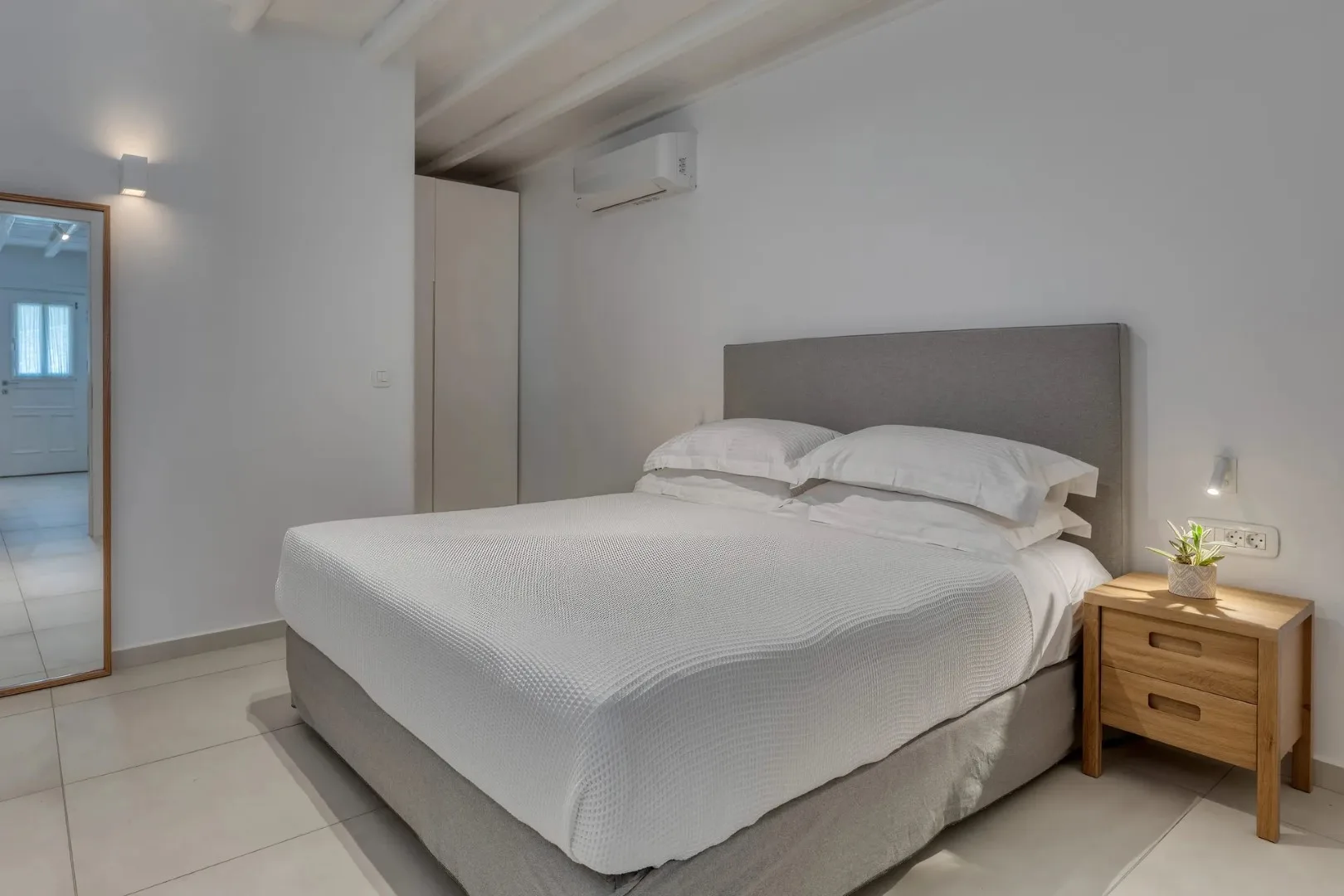 Un dormitorio con una cama bien hecha y una mesita de noche de madera.