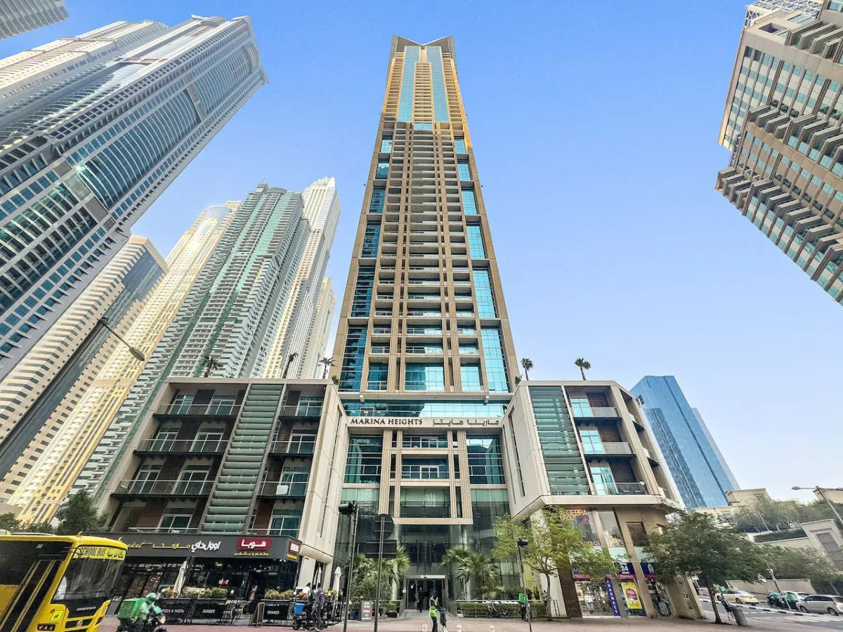 Una alta torre hotelera moderna se alza entre edificios altos bajo un cielo despejado.