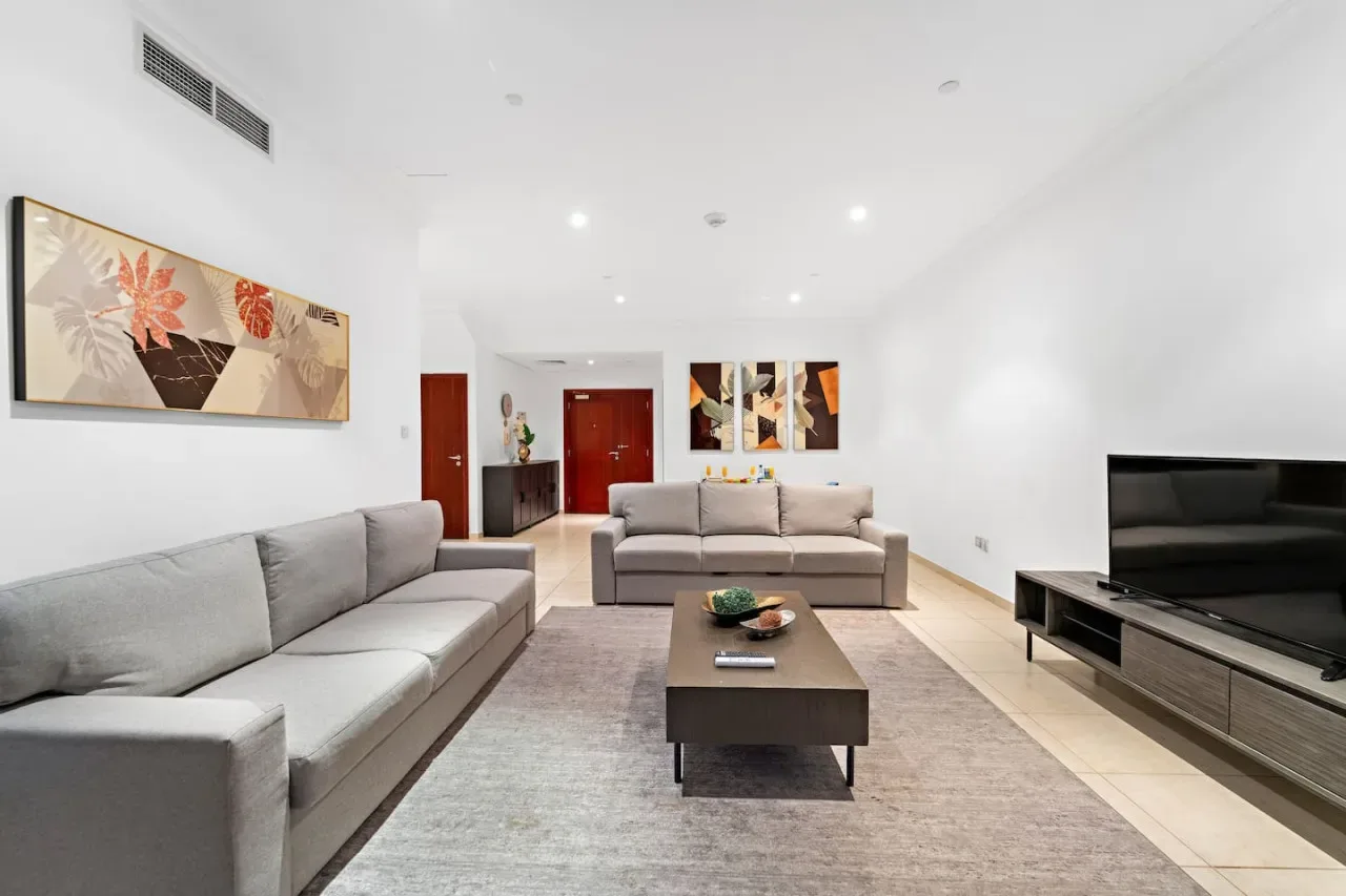 Una sala de estar luminosa con asientos alrededor de una mesa de centro y un televisor.