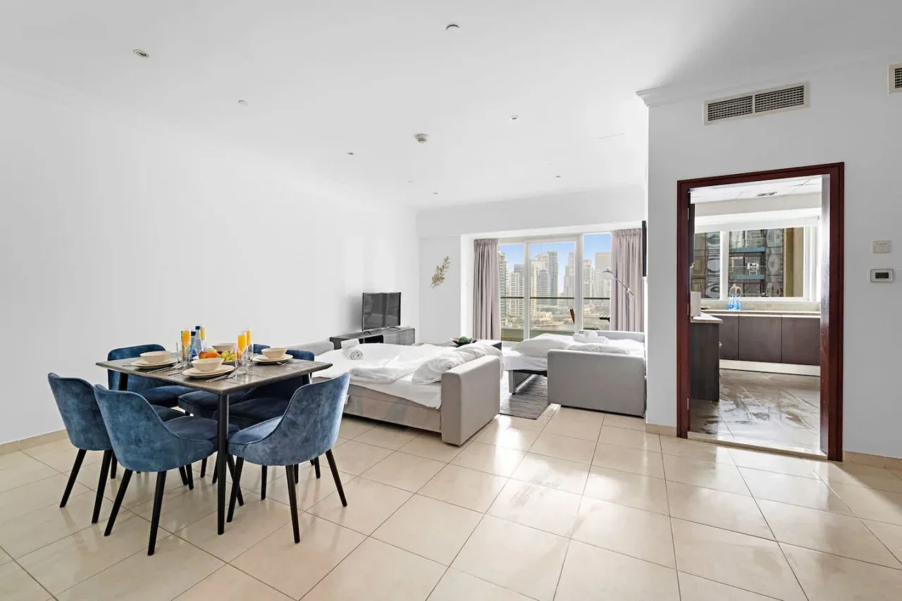 Una luminosa sala de estar y comedor abiertos, con asientos junto a las ventanas.