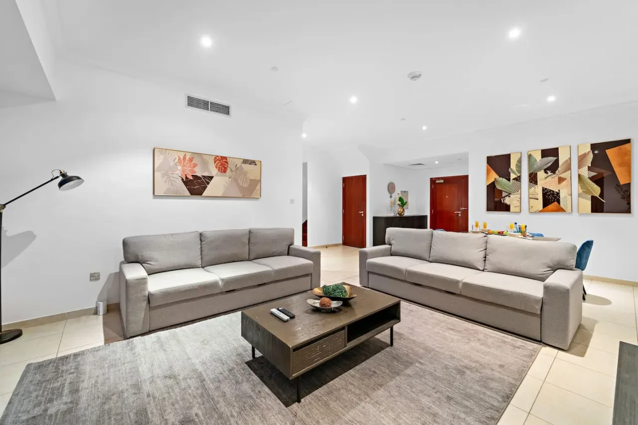 Una sala luminosa con dos zonas de descanso y una mesa de centro.