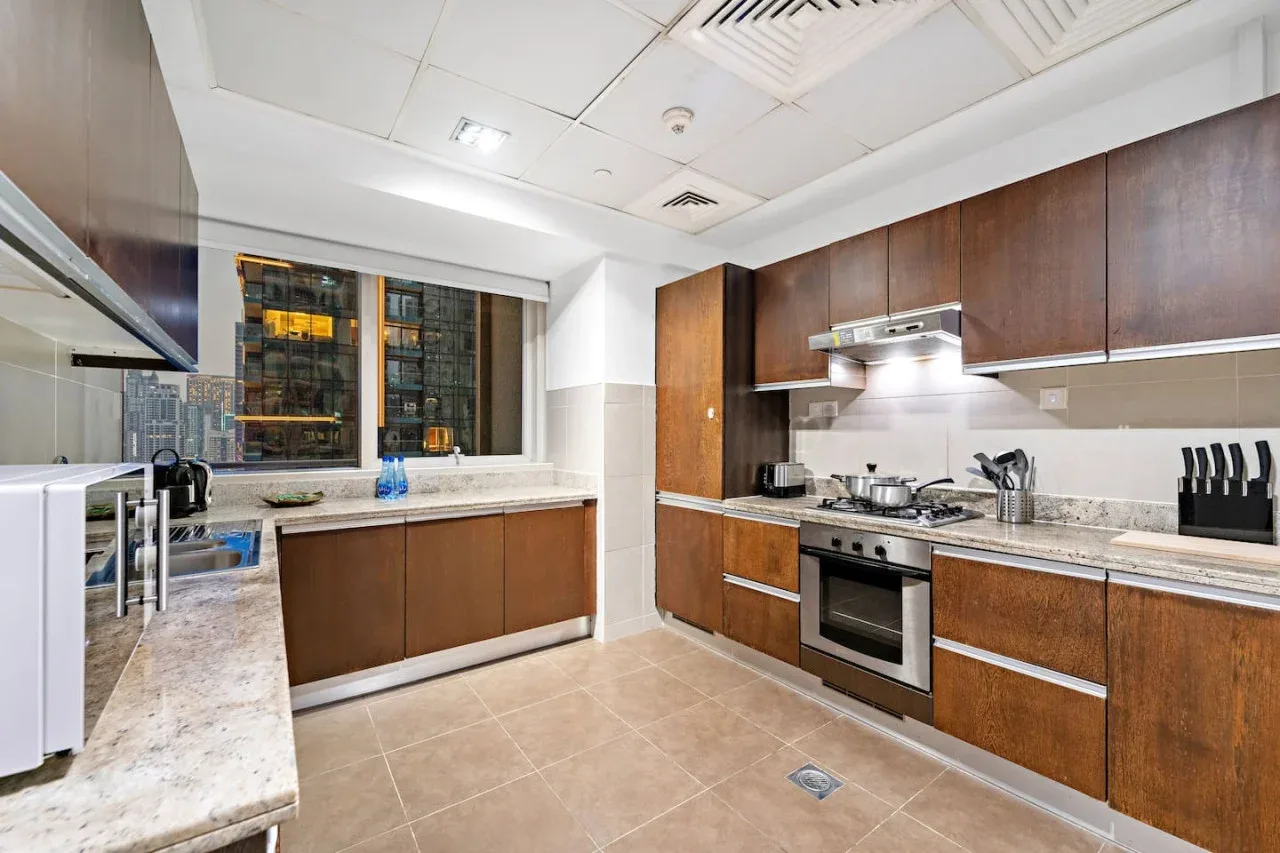 Una cocina moderna con gabinetes de madera, encimeras de piedra y electrodomésticos de acero inoxidable.