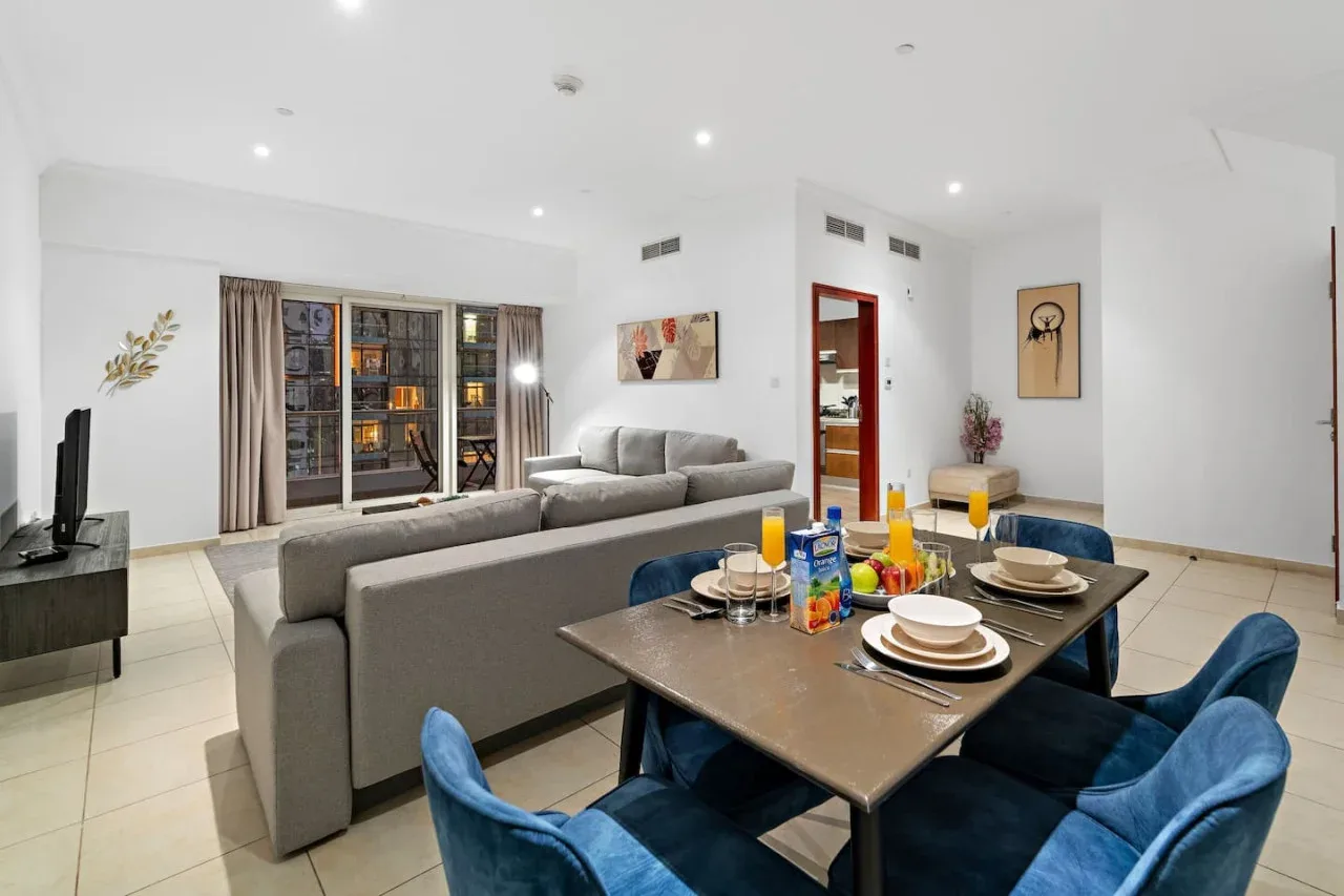 Una luminosa sala de estar y comedor de concepto abierto, con asientos grises y una mesa puesta.