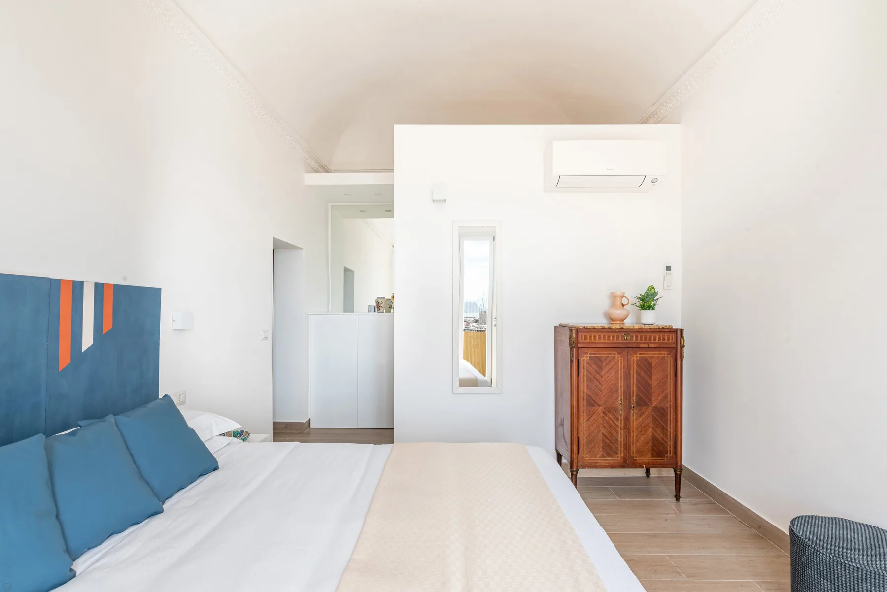 Un dormitorio luminoso con ropa de cama azul y un armario de madera.