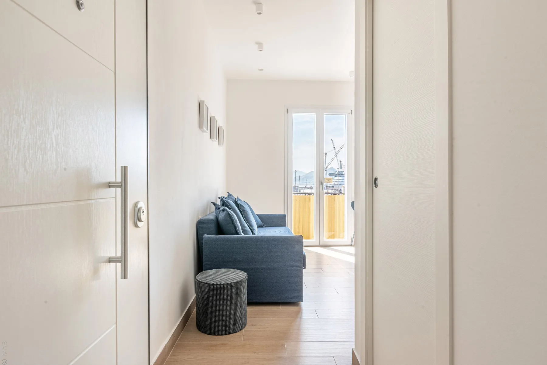 A bright living area with blue seating and glass doors opening onto a balcony.