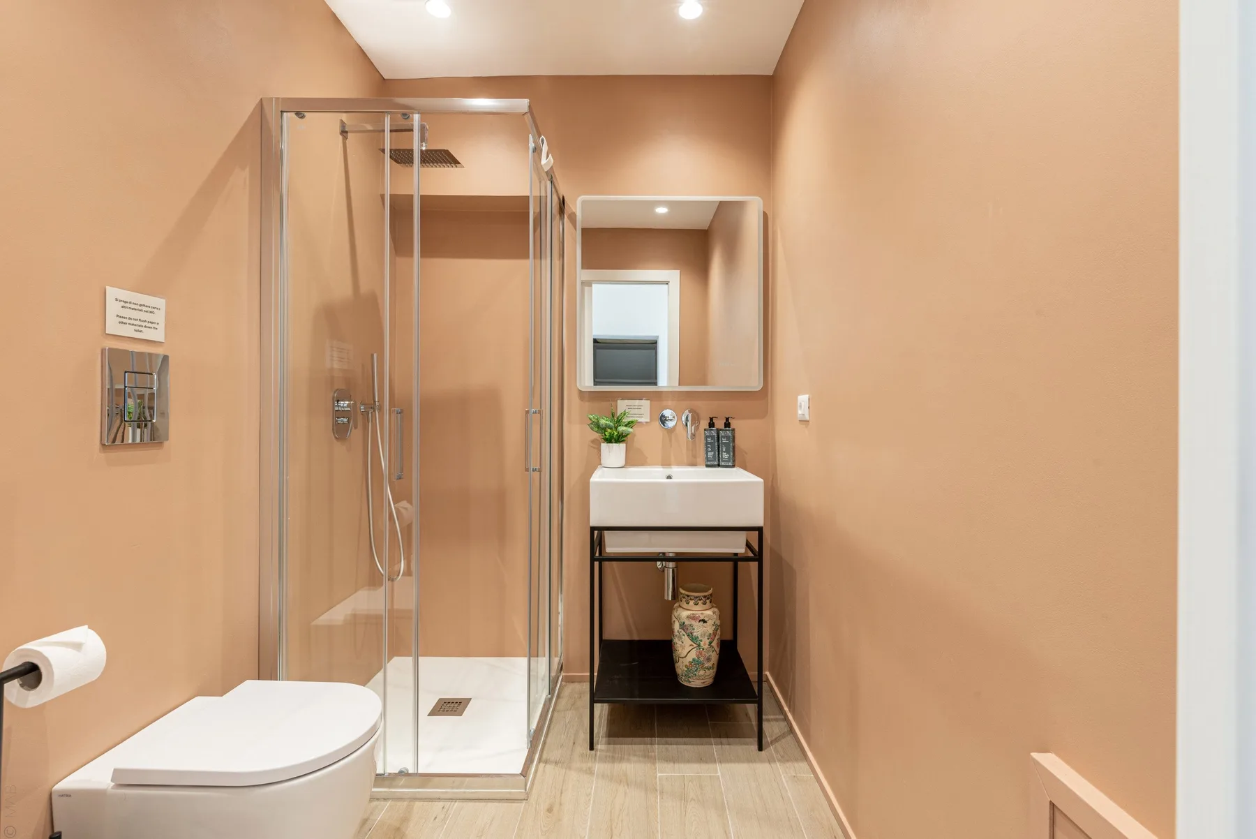 Un baño con una ducha de vidrio y un lavabo bajo un espejo.