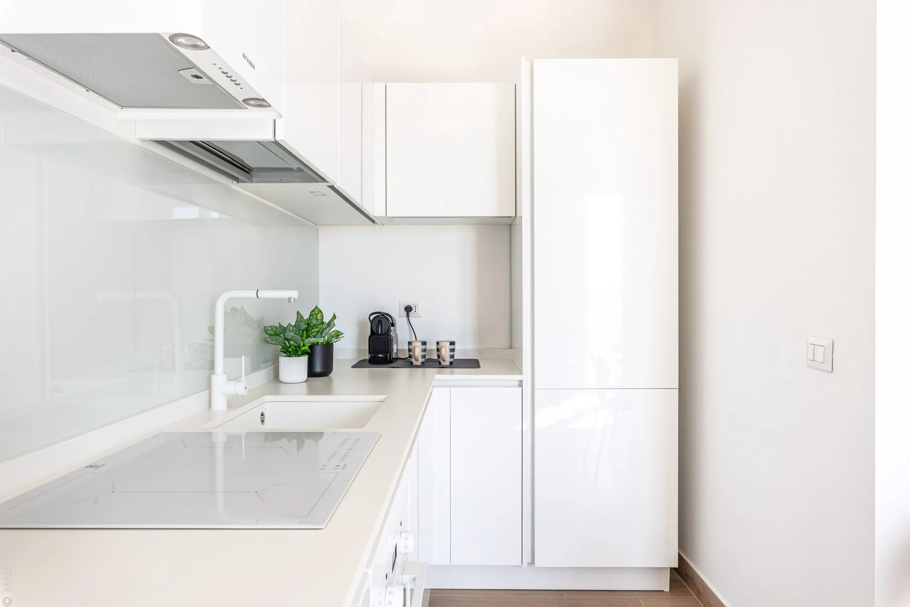 Una cocina luminosa con armarios blancos, una encimera y una placa de cocina.