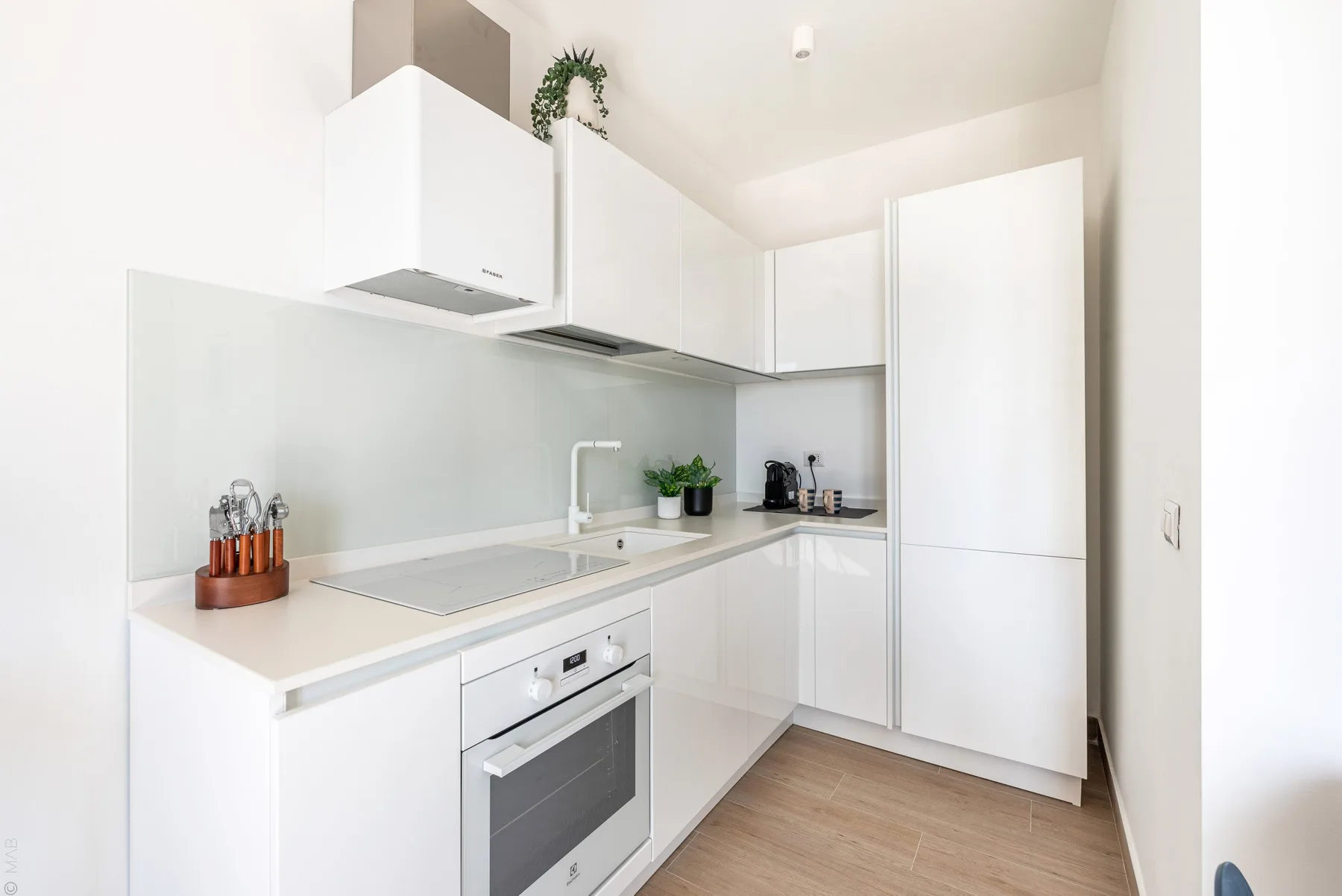 Una cocina moderna y luminosa con gabinetes blancos y una placa de cocina en la encimera.