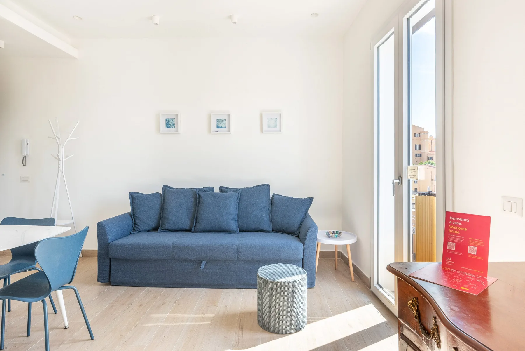 Una sala luminosa con asientos azules y ventanas altas.
