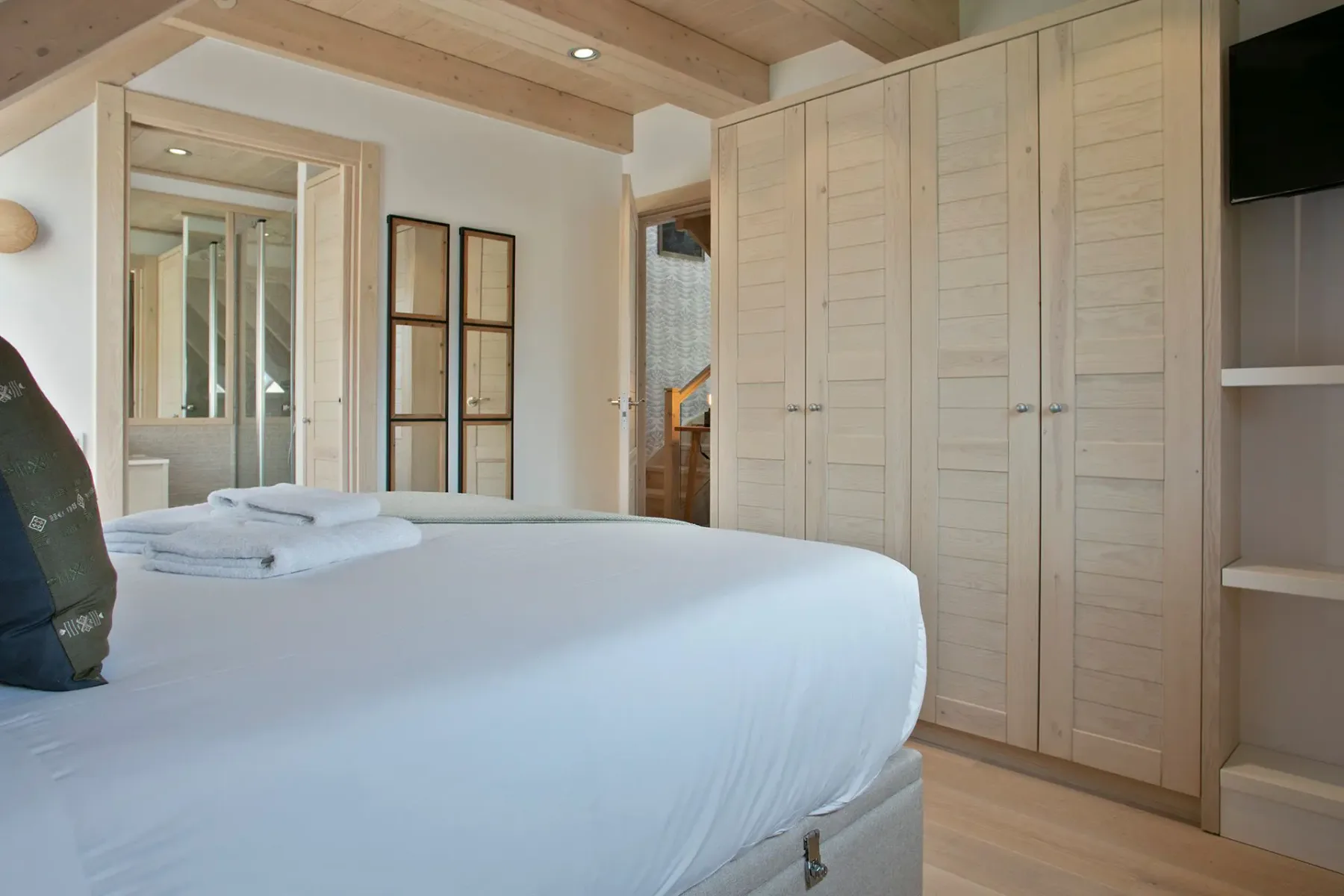 A bedroom with a neatly made bed and built-in wardrobes.
