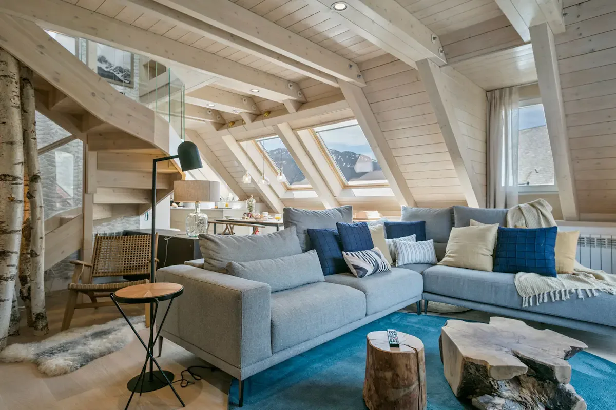 A bright living room with a sectional seating area beneath sloped wooden ceilings.