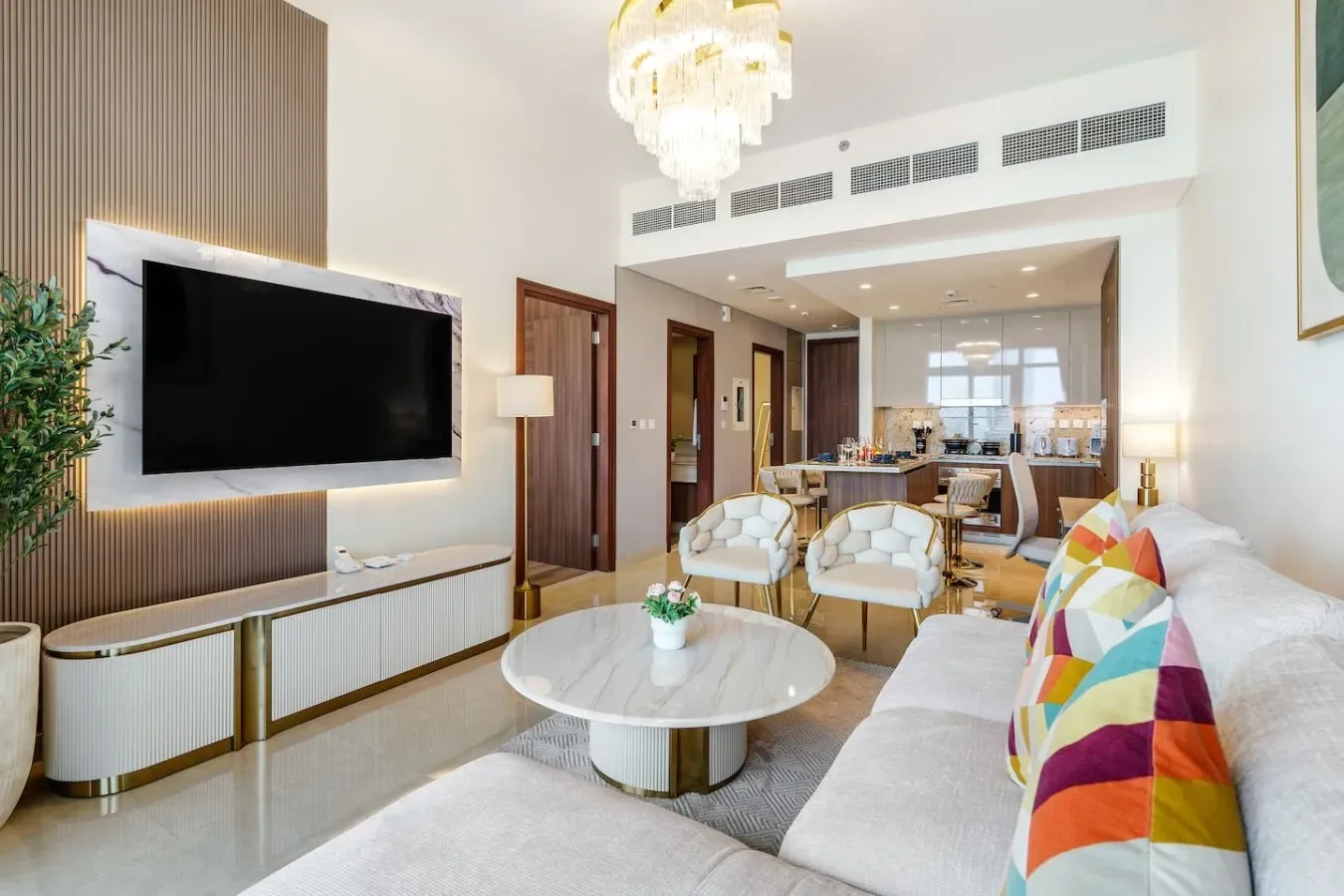 Una luminosa sala de estar con asientos, un televisor en la pared y un comedor al fondo.