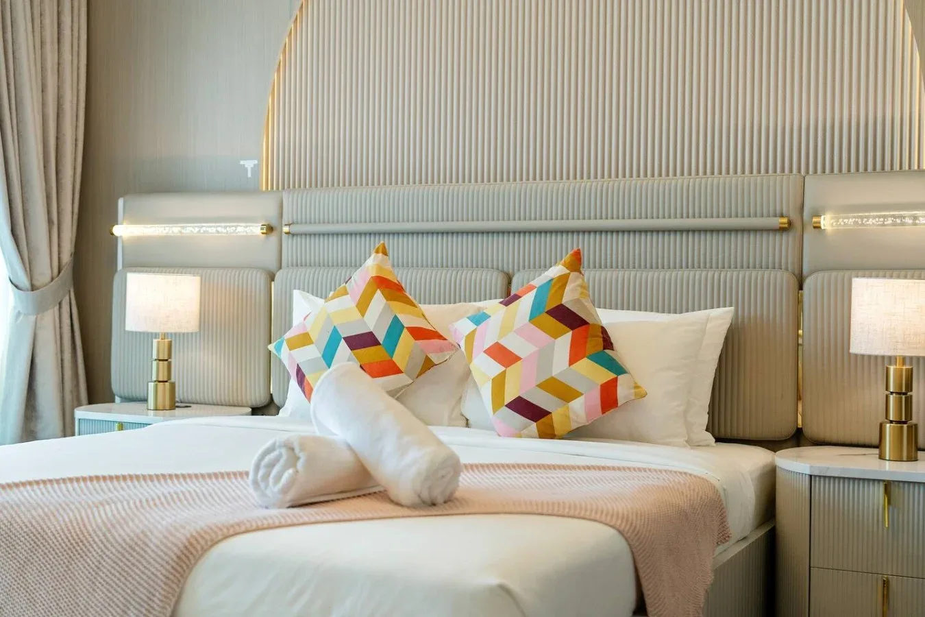 Un dormitorio con una cama bien arreglada y cojines geométricos de colores.