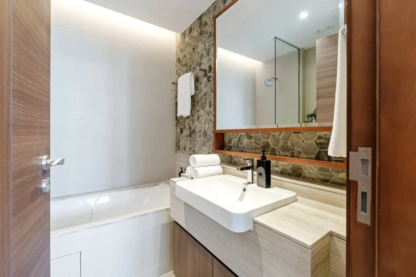 Un baño moderno con bañera, lavabo y un espejo grande.