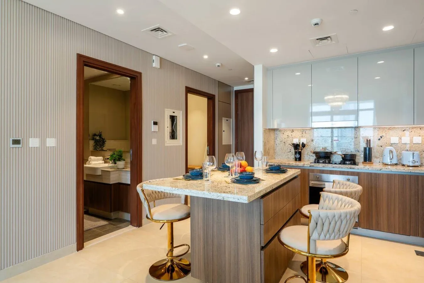 Una cocina moderna con una isla central, asientos y armarios en la pared del fondo.