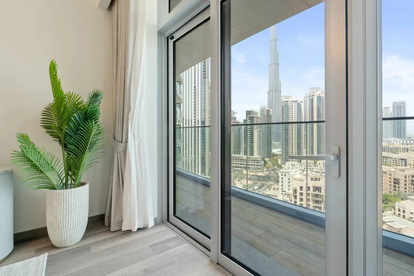 Una habitación luminosa da a un balcón con vistas al horizonte de la ciudad.