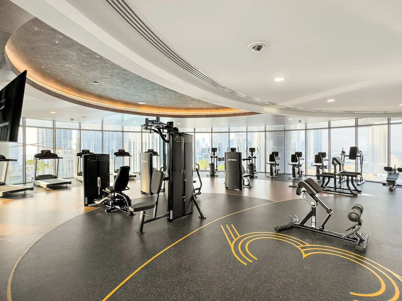 Un gimnasio amplio con máquinas de ejercicio junto a grandes ventanales.