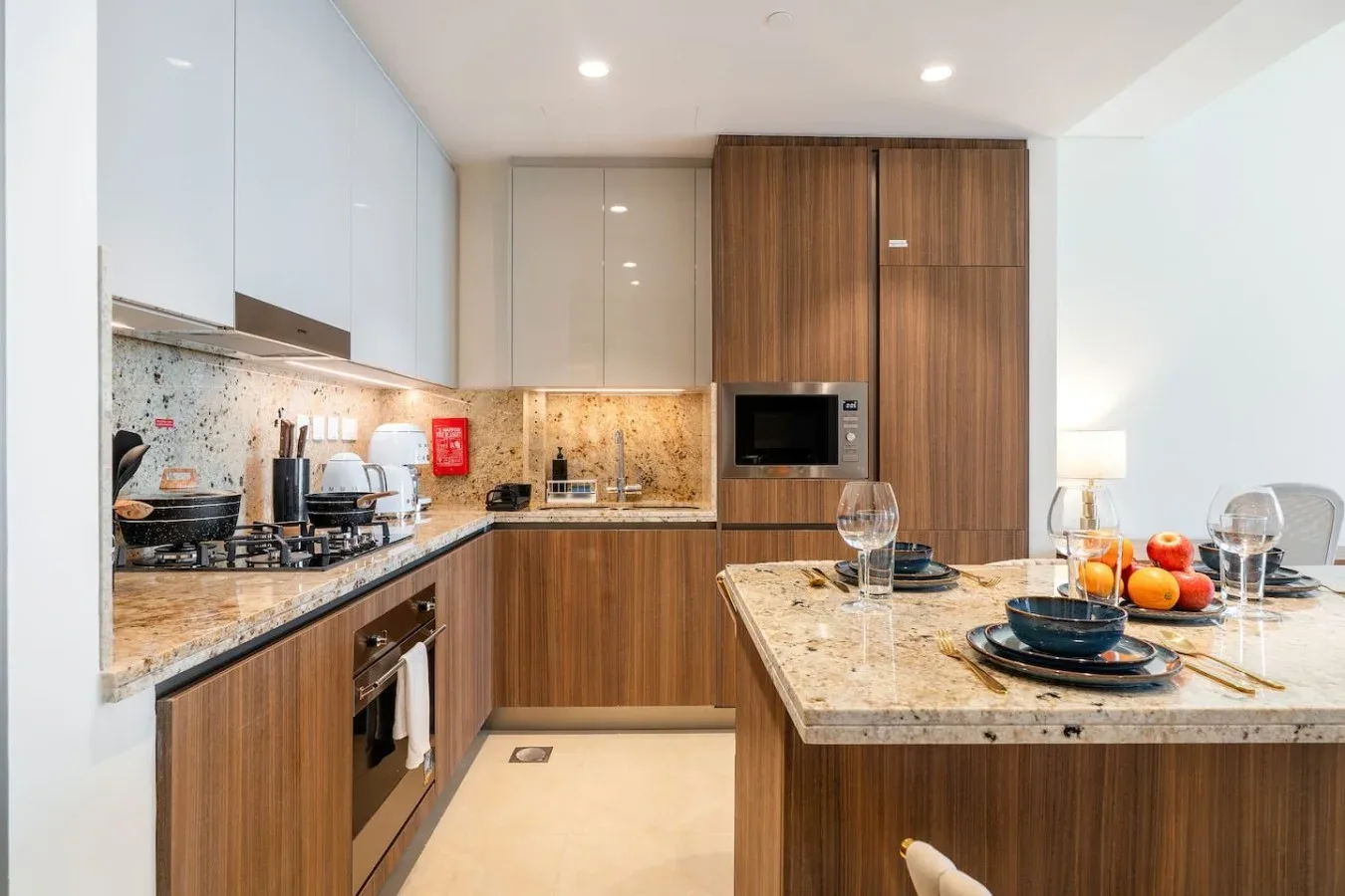Una cocina moderna con gabinetes de madera, horno empotrado y una barra preparada con platos.
