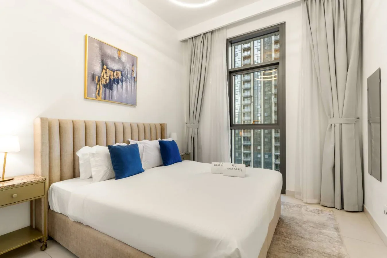 Un dormitorio luminoso con una cama tendida y cortinas largas.