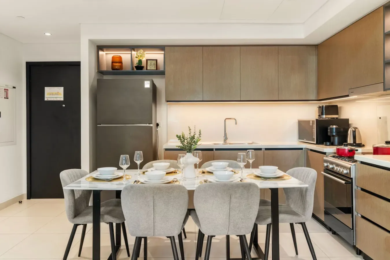 Una mesa puesta con platos y vasos está en una cocina moderna.