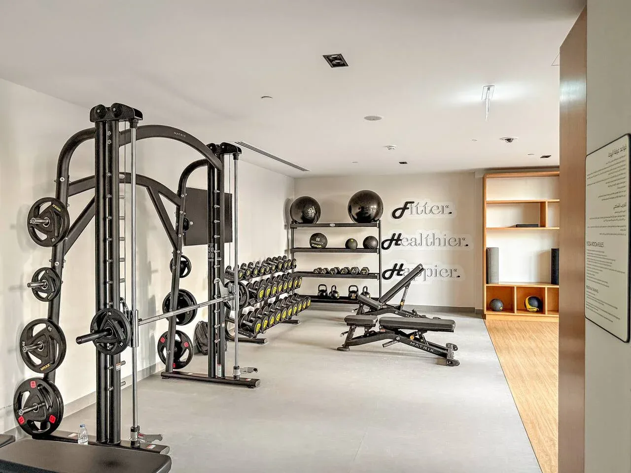Un gimnasio con máquinas de pesas, mancuernas y bancos de ejercicio.