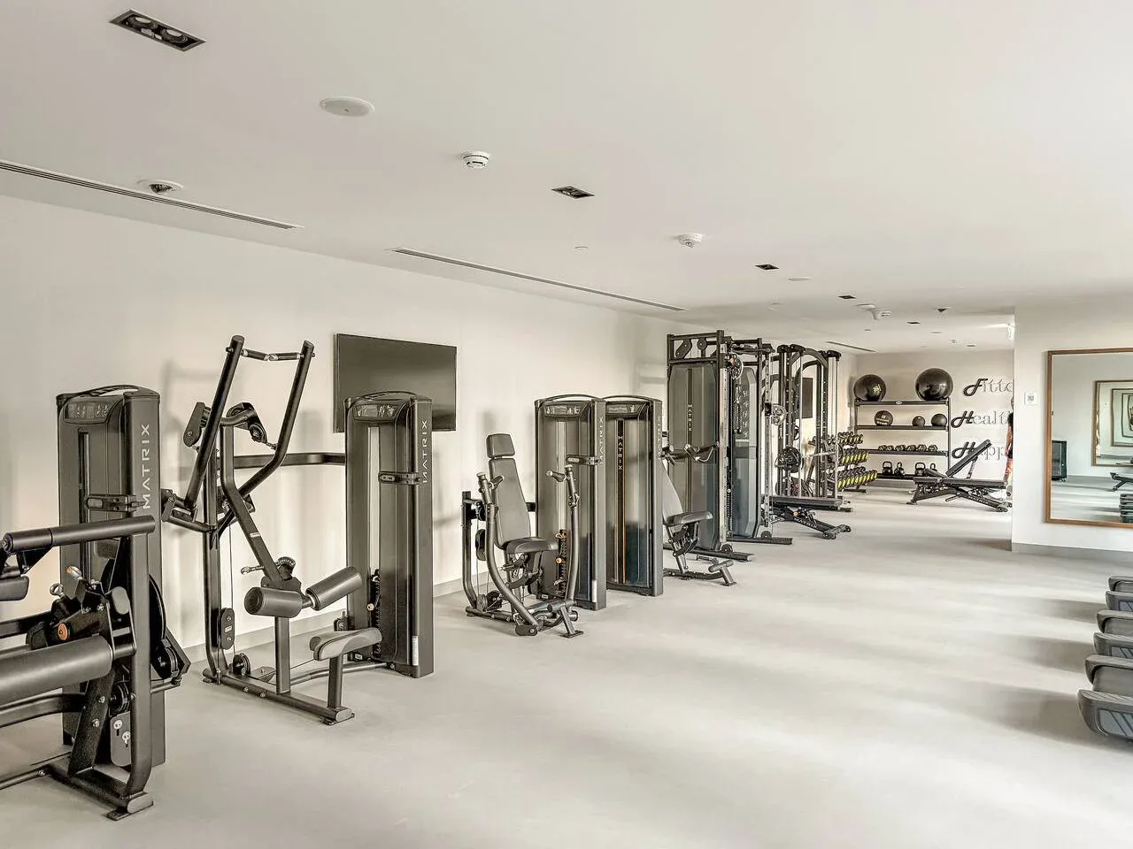 Un gimnasio con máquinas de pesas, equipo de ejercicio y espacio libre.