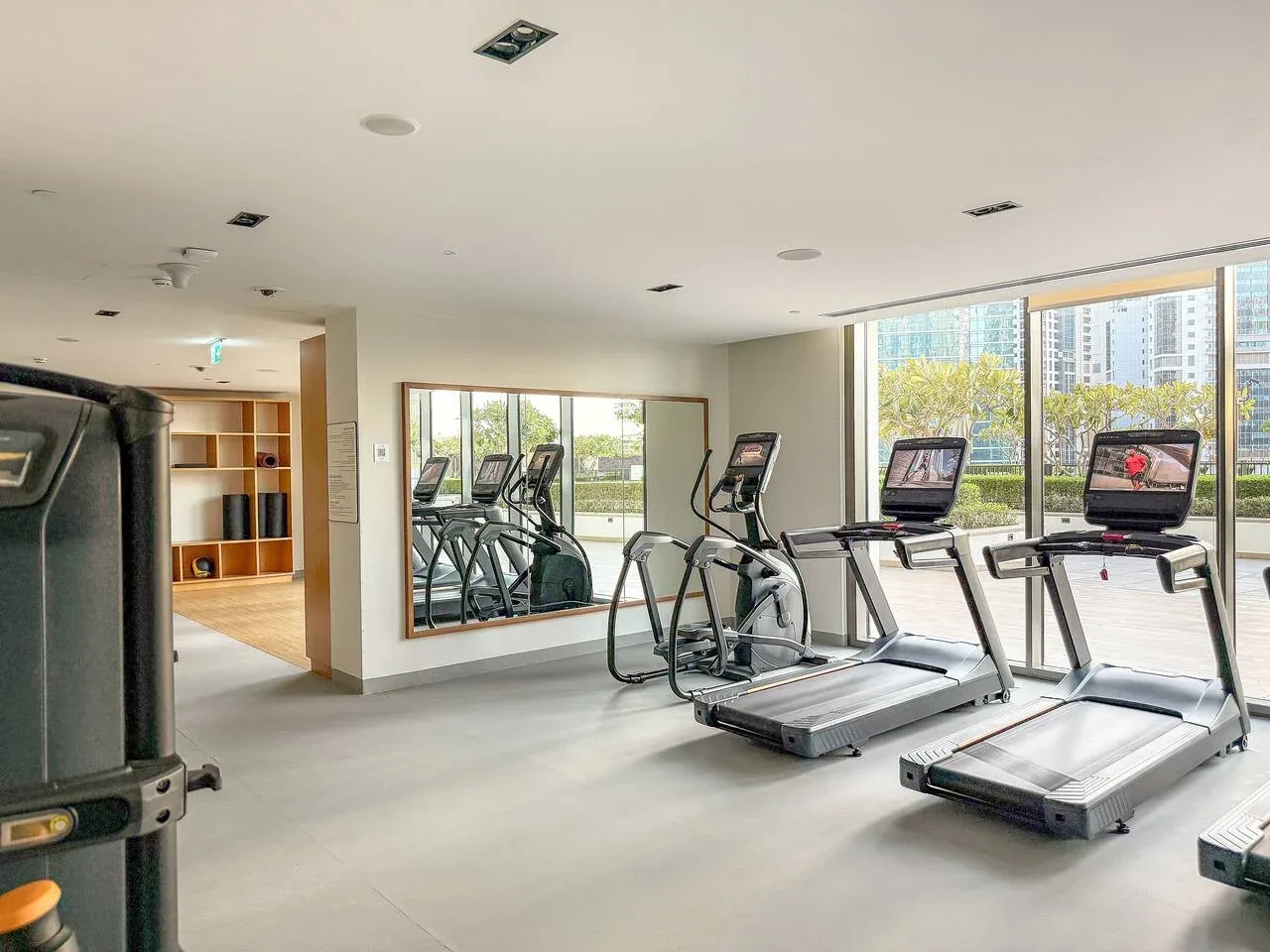 Una sala de entrenamiento con cintas de correr, bicicletas estáticas y grandes ventanales.