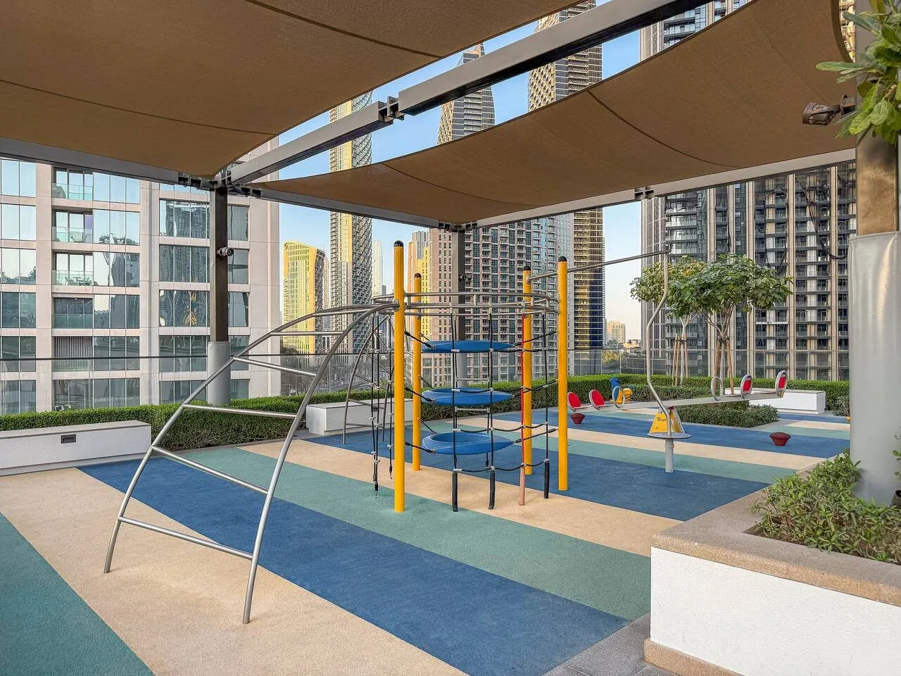 Un parque infantil al aire libre con estructuras para trepar y pavimento de colores.