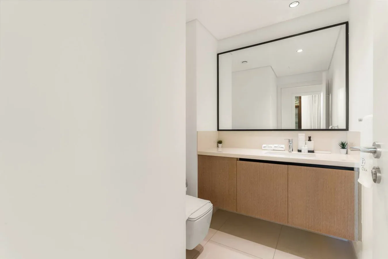 Un baño luminoso con un tocador largo, lavabo y un gran espejo de pared.