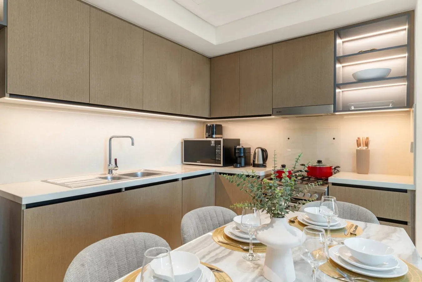Una cocina moderna con una mesa puesta con platos y flores.