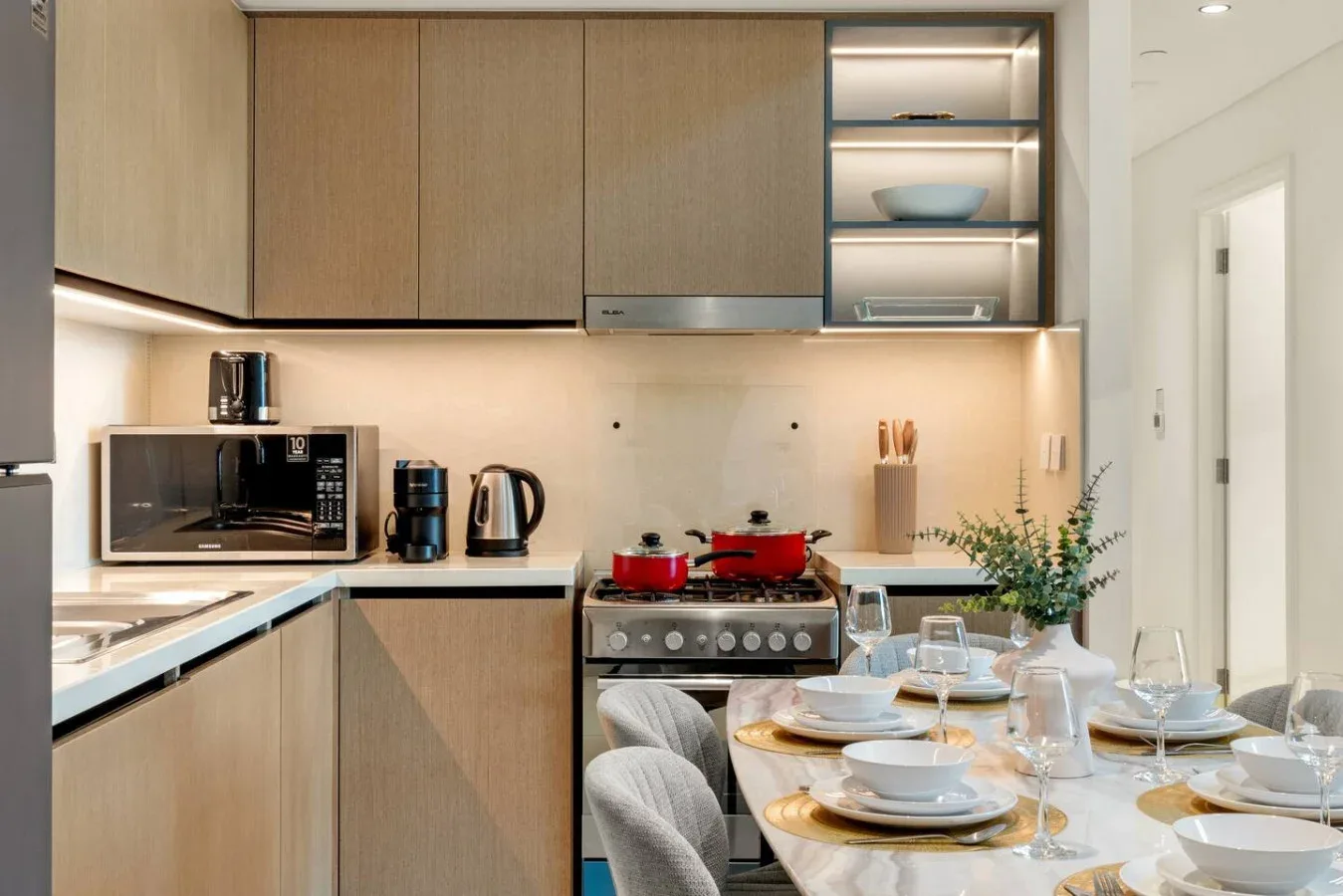 Una cocina moderna con una mesa puesta junto a la zona de cocina.