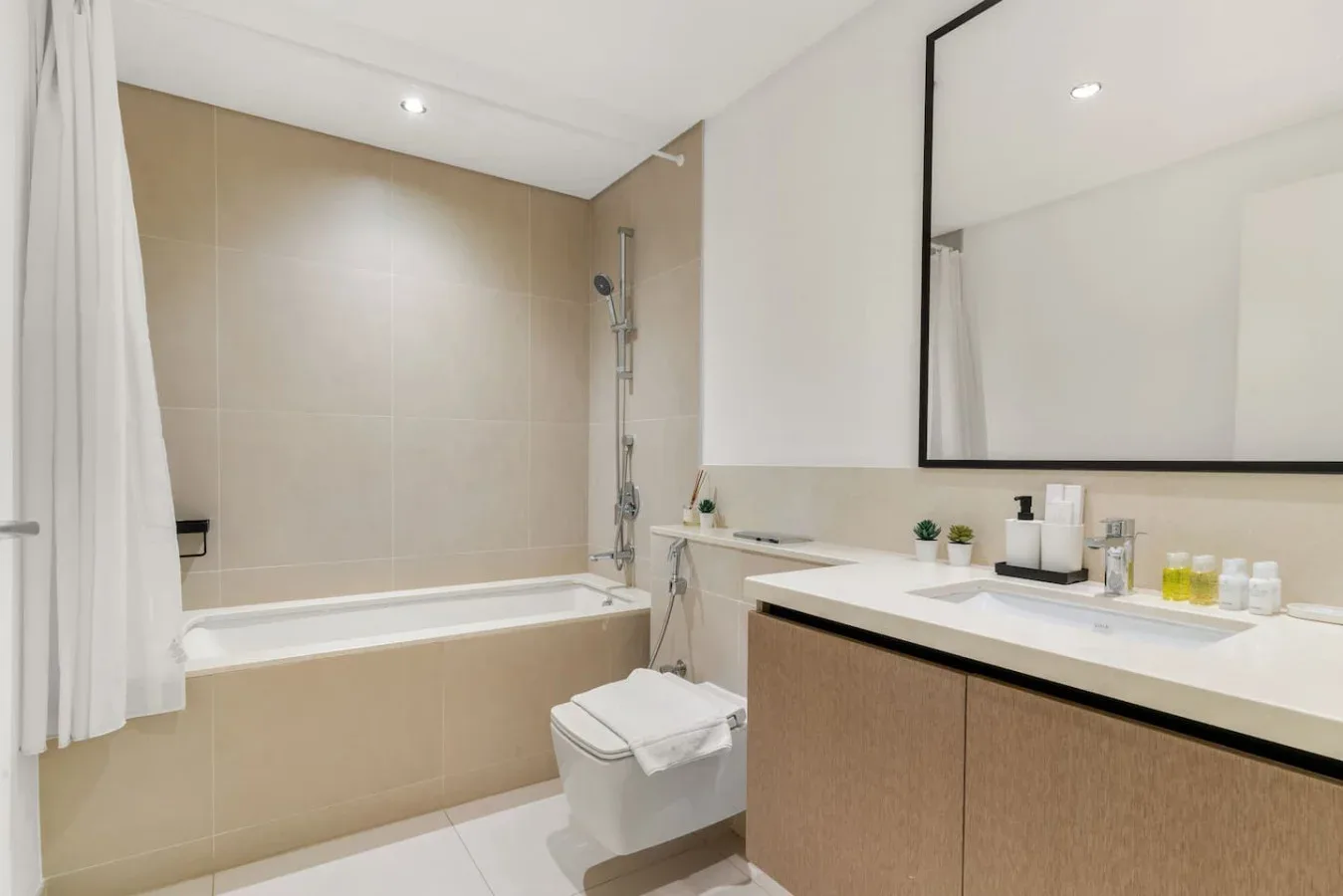 Un baño con bañera, ducha y un largo tocador bajo un espejo.