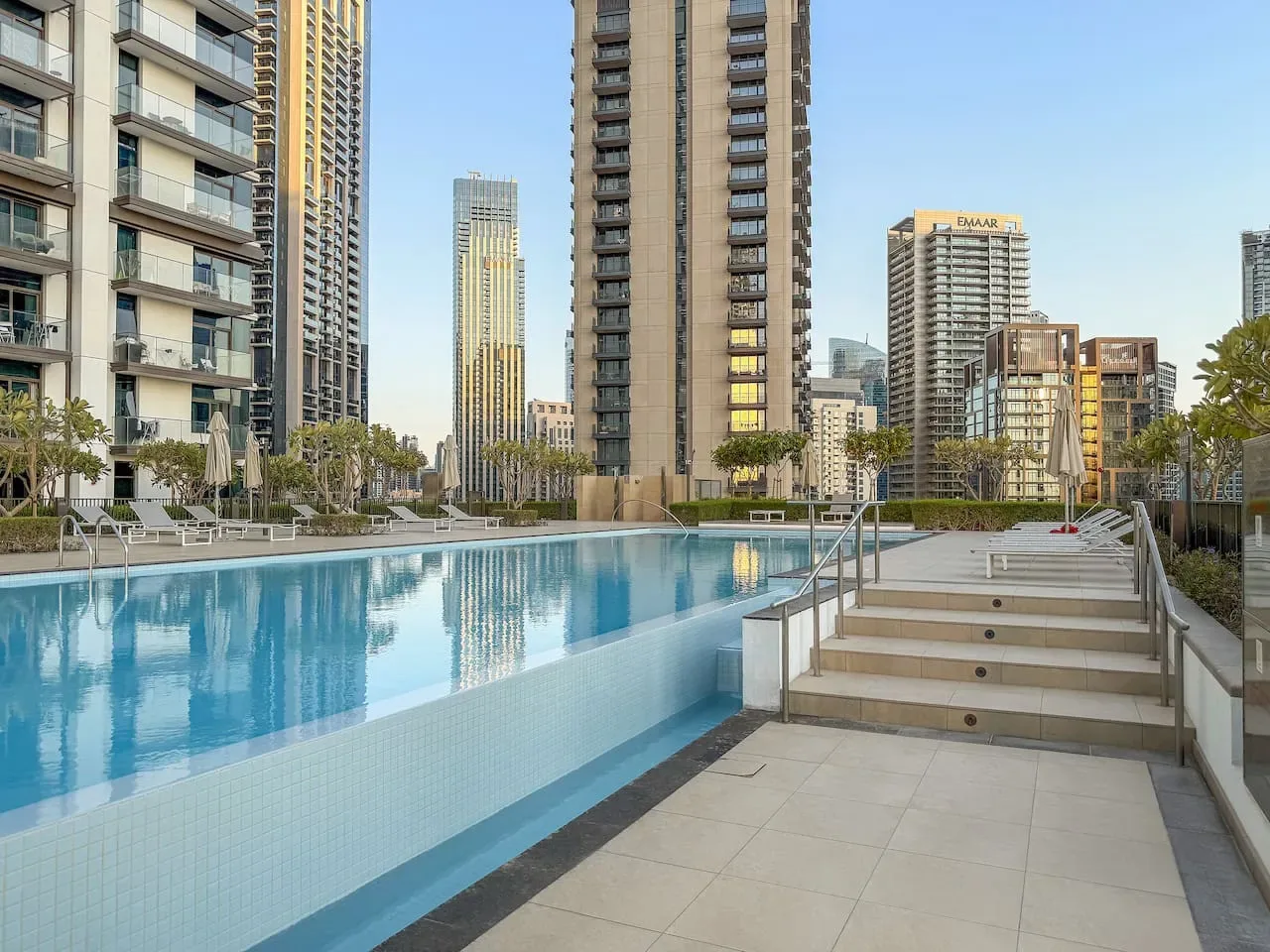 Una piscina y escalones con azulejos están rodeados de edificios altos.