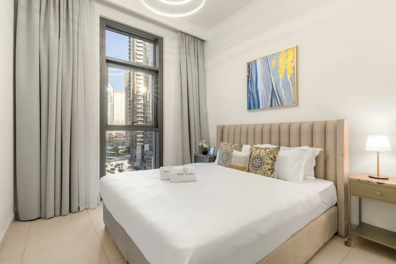 Un dormitorio con una cama junto a una gran ventana con cortinas y edificios de la ciudad.