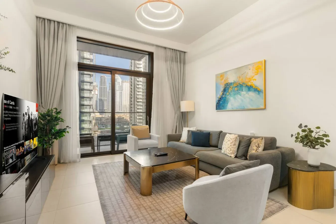 Una sala luminosa con asientos alrededor de una mesa de centro junto a grandes ventanas.